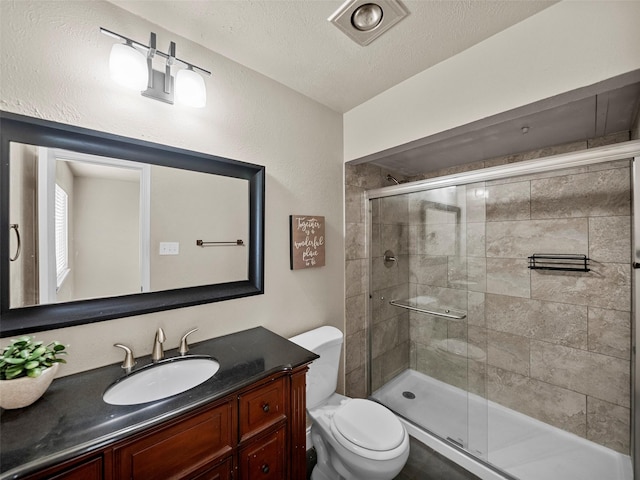 bathroom featuring toilet, a shower stall, a textured ceiling, and vanity