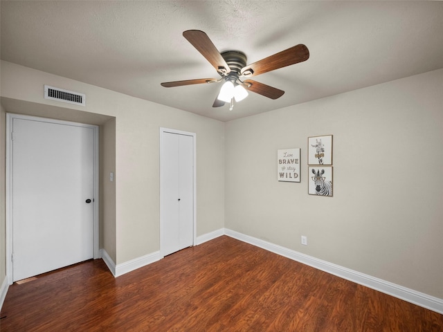 unfurnished bedroom featuring baseboards, visible vents, a ceiling fan, wood finished floors, and a closet