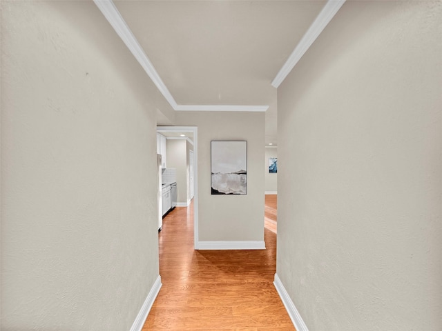 hall featuring ornamental molding, light wood-style flooring, and baseboards