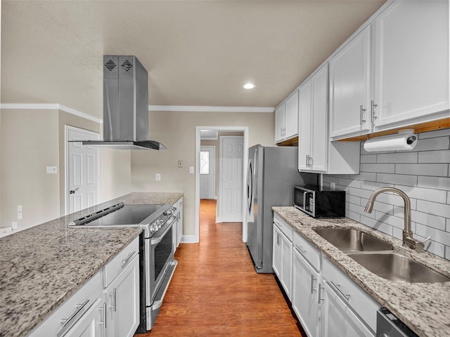 kitchen with stainless steel appliances, ornamental molding, white cabinetry, a sink, and wall chimney exhaust hood