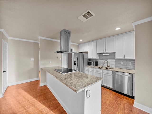 kitchen featuring island range hood, stainless steel appliances, a sink, visible vents, and light wood-style floors