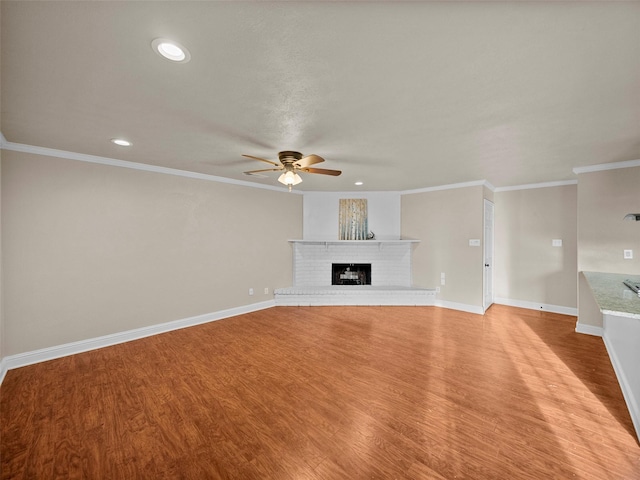 unfurnished living room featuring light wood finished floors, baseboards, a ceiling fan, crown molding, and a fireplace