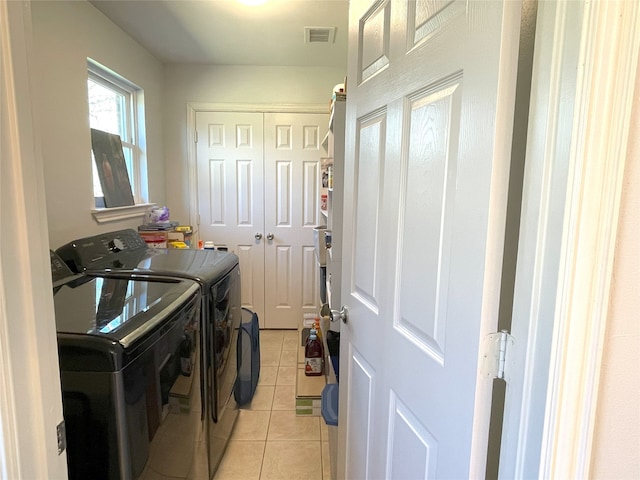 clothes washing area featuring laundry area, light tile patterned floors, visible vents, and washing machine and clothes dryer