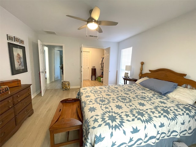 bedroom with baseboards, light wood finished floors, visible vents, and a ceiling fan