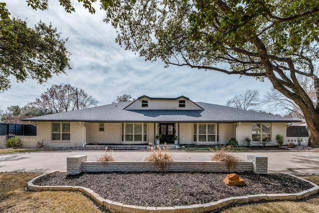 view of front of home with a shingled roof and brick siding