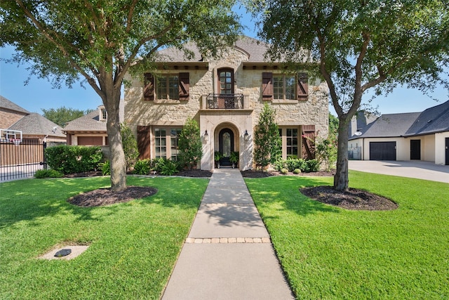 view of front of home with stone siding, a front lawn, fence, and a balcony