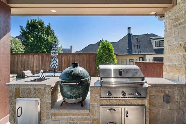 view of patio featuring fence, grilling area, and a sink