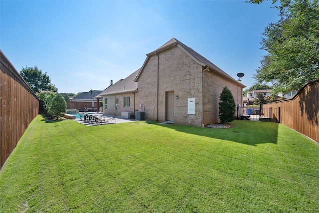 rear view of house with brick siding, a yard, a patio, central AC, and a fenced backyard