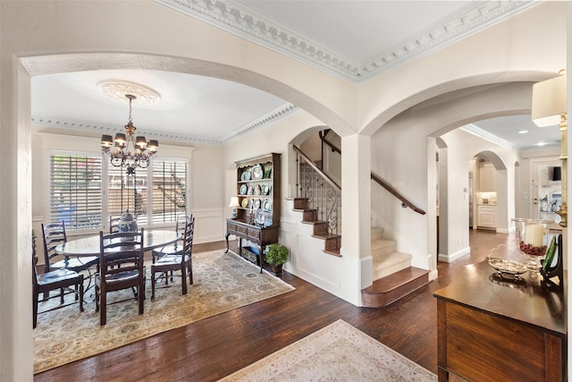 dining space with a wainscoted wall, stairway, ornamental molding, wood finished floors, and a chandelier