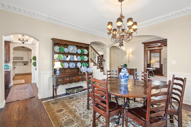 dining space with arched walkways, wainscoting, wood finished floors, and an inviting chandelier