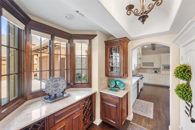 interior space with arched walkways, stainless steel microwave, dark wood finished floors, and visible vents