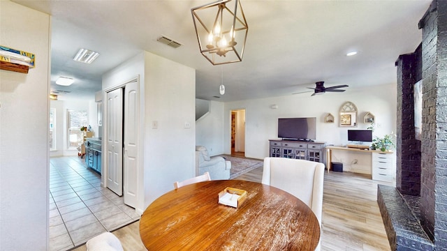 dining room featuring light wood-style floors, visible vents, and ceiling fan with notable chandelier