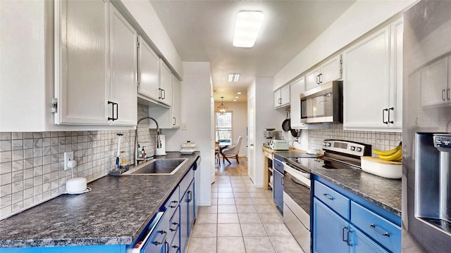 kitchen featuring blue cabinets, dark countertops, appliances with stainless steel finishes, and a sink