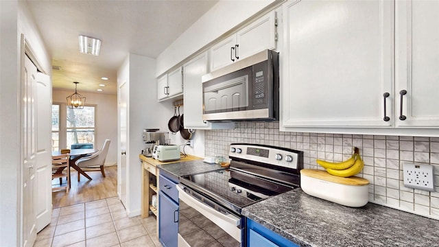 kitchen featuring light tile patterned floors, blue cabinets, stainless steel appliances, white cabinetry, and backsplash