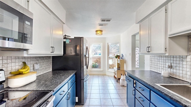 kitchen featuring a sink, appliances with stainless steel finishes, dark countertops, and blue cabinetry