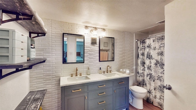 bathroom featuring toilet, a textured ceiling, double vanity, and a sink