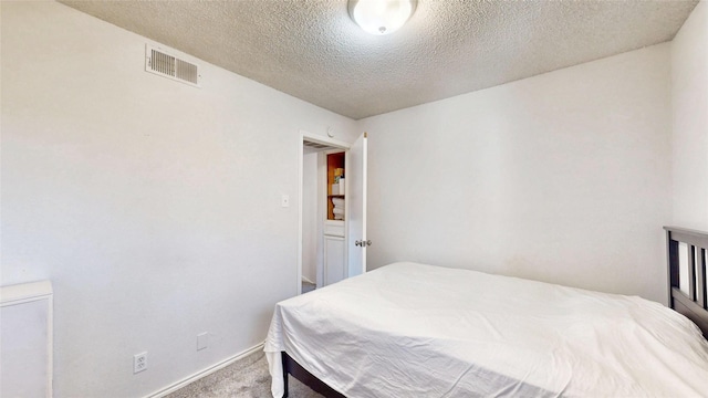 carpeted bedroom with visible vents, a textured ceiling, and baseboards