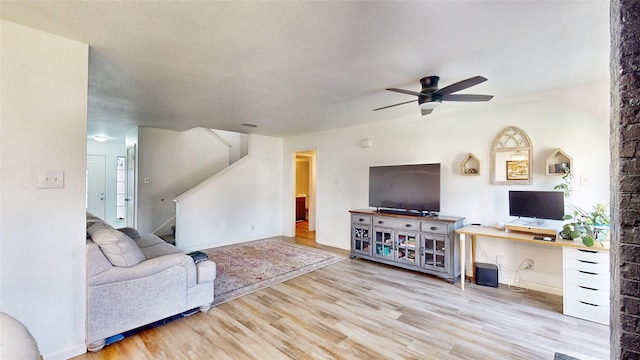 living room with a ceiling fan, stairway, and wood finished floors