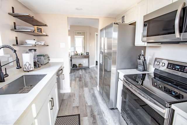 kitchen featuring white cabinets, appliances with stainless steel finishes, open shelves, and a sink