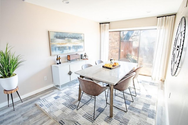 dining space featuring baseboards and light wood finished floors