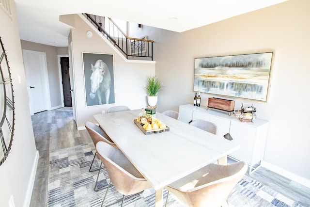 dining room featuring light wood-type flooring, stairs, and baseboards