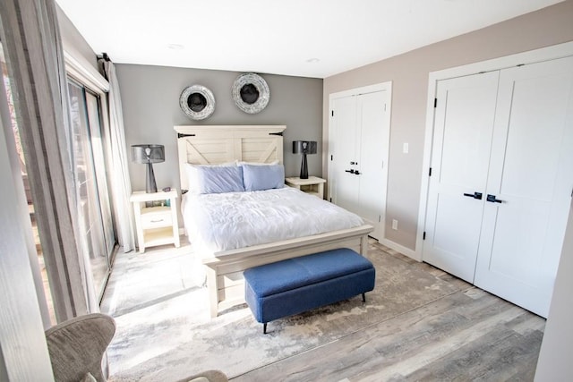 bedroom featuring baseboards, wood finished floors, and multiple closets