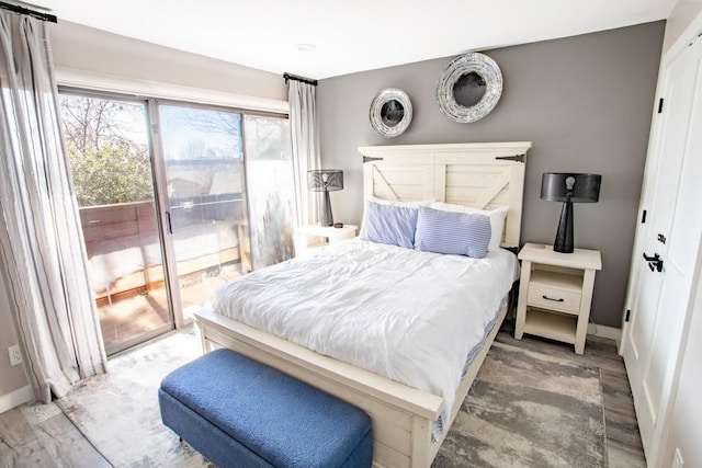 bedroom with baseboards, wood finished floors, and access to exterior