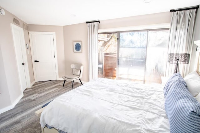 bedroom featuring access to exterior, visible vents, baseboards, and wood finished floors