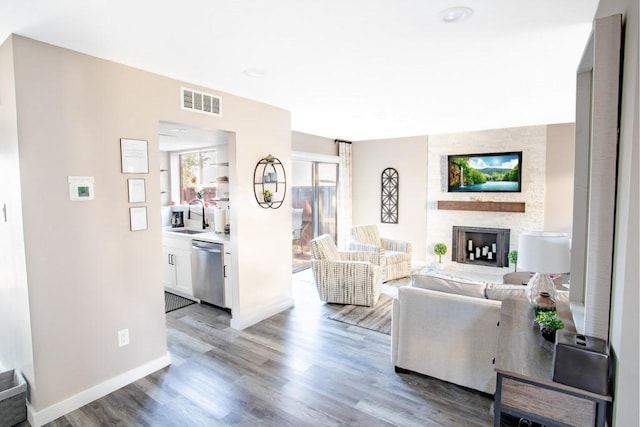 living room with a large fireplace, visible vents, light wood-style flooring, and baseboards