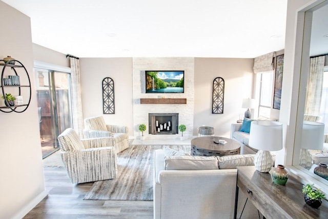 living area featuring a fireplace, wood finished floors, and baseboards