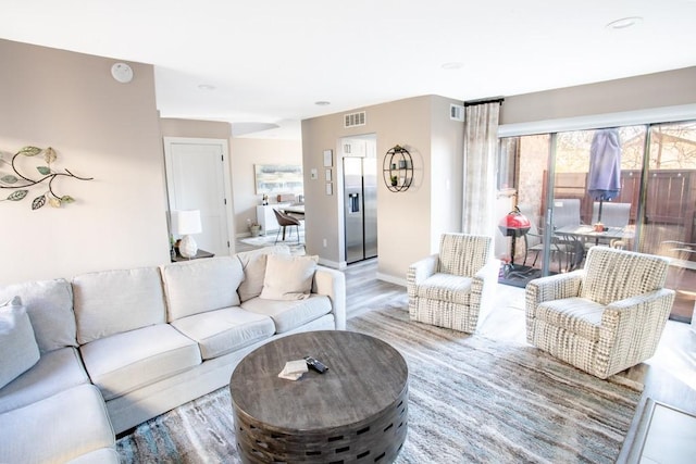 living area with wood finished floors, visible vents, and baseboards