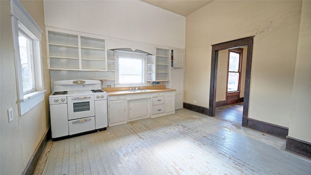 kitchen featuring open shelves, range with two ovens, a sink, and light wood-style flooring