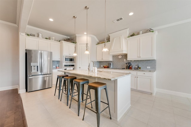 kitchen with visible vents, ornamental molding, a kitchen breakfast bar, stainless steel appliances, and a sink