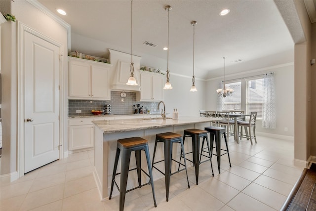 kitchen featuring light tile patterned floors, a kitchen breakfast bar, white cabinets, and decorative backsplash