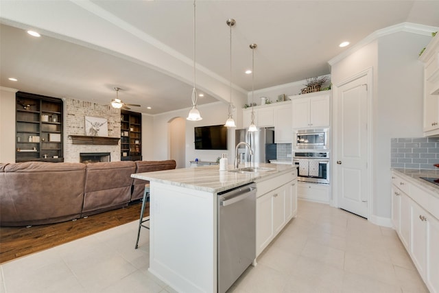 kitchen with ornamental molding, appliances with stainless steel finishes, arched walkways, and a sink