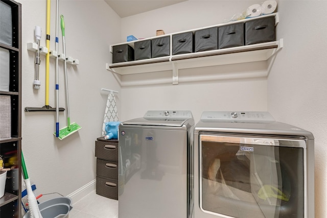 washroom with laundry area, baseboards, separate washer and dryer, and tile patterned floors