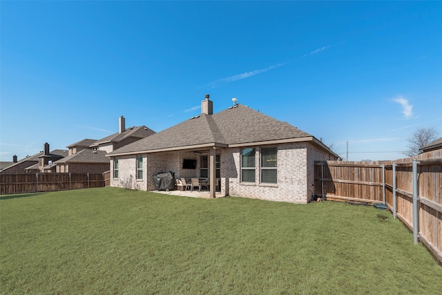 rear view of house with a yard, a fenced backyard, brick siding, and a patio