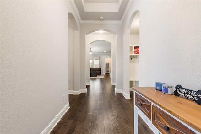 corridor with arched walkways, a textured wall, dark wood-type flooring, ornamental molding, and baseboards