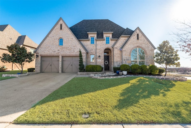 french country inspired facade with driveway, brick siding, a front lawn, and a shingled roof