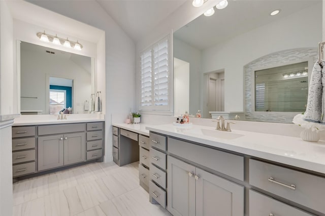 full bathroom featuring lofted ceiling, a tile shower, two vanities, and a sink