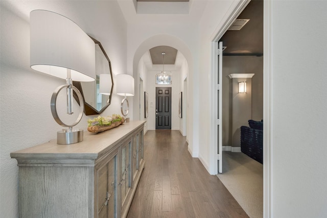 hallway featuring baseboards, wood finished floors, visible vents, and arched walkways