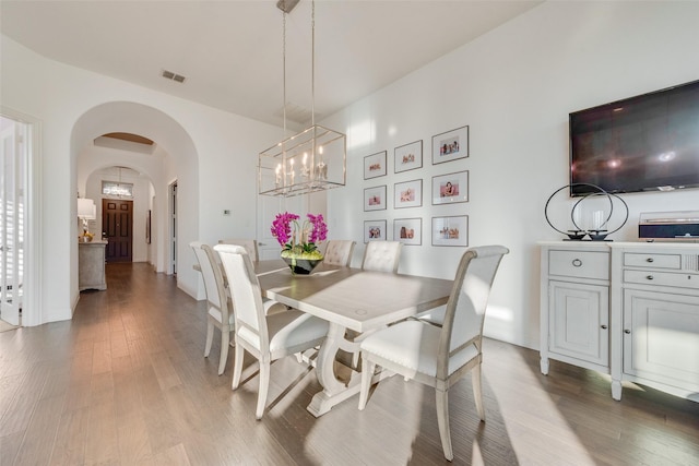 dining area featuring arched walkways, visible vents, light wood-style flooring, and an inviting chandelier