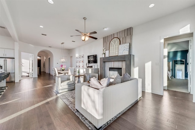 living room with dark wood-style floors, arched walkways, a ceiling fan, and recessed lighting