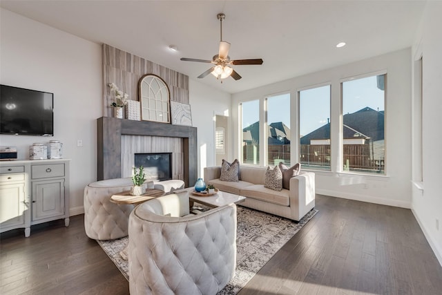 living area featuring a ceiling fan, a large fireplace, baseboards, and dark wood-style flooring