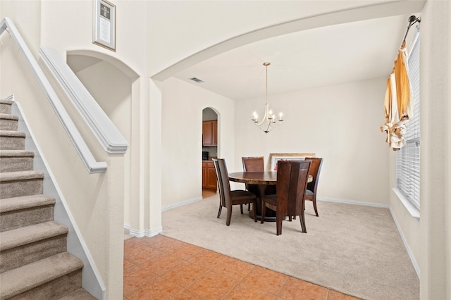 dining area with arched walkways, light tile patterned flooring, light colored carpet, stairs, and an inviting chandelier