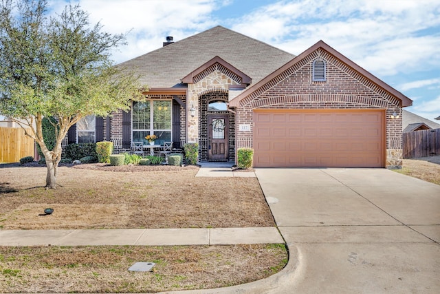 french country style house with concrete driveway, stone siding, an attached garage, fence, and brick siding