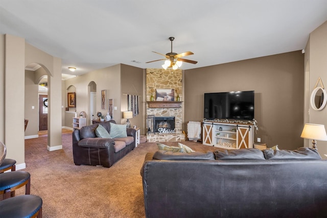 living room featuring carpet, arched walkways, a fireplace, visible vents, and baseboards