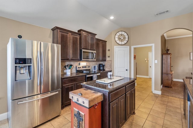 kitchen featuring visible vents, arched walkways, a kitchen island, appliances with stainless steel finishes, and light tile patterned flooring