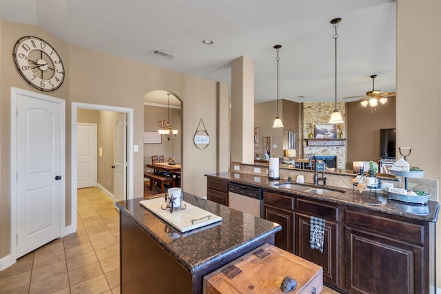 kitchen with a center island, arched walkways, open floor plan, a sink, and dishwasher