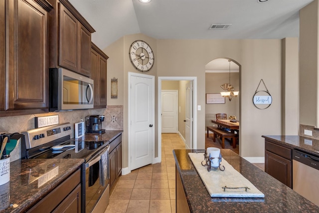 kitchen with visible vents, decorative backsplash, arched walkways, dark stone counters, and appliances with stainless steel finishes